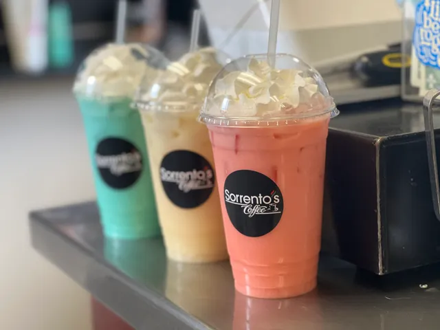 Three whipped-cream-topped Sorrento's Coffee drinks in green, yellow, and pink